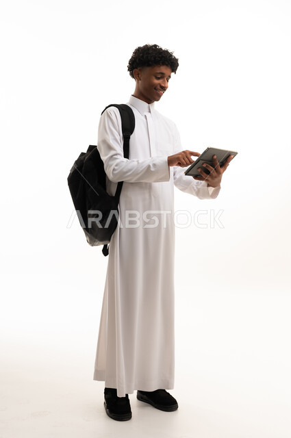 طالب سعودي يحمل تابلت وحقيبة ظهر بخلفية بيضاء