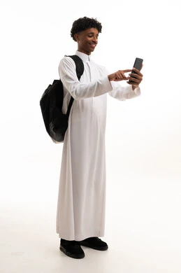 رجل سعودي بالثوب الأبيض يستخدم الهاتف مع حقيبة ظهر