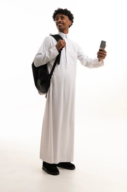 طالب سعودي بالثوب التقليدي يحمل هاتفاً ذكياً