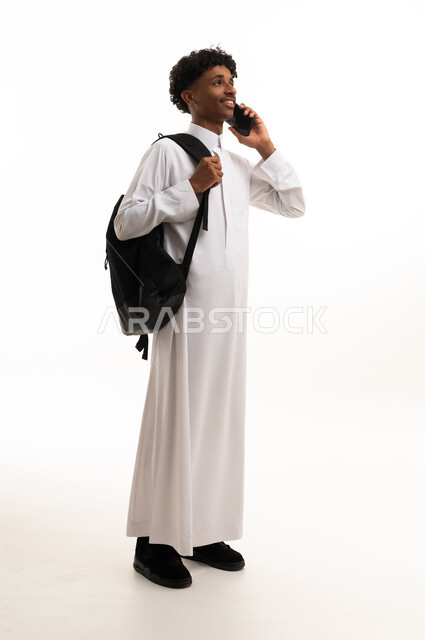 شاب سعودي بالثوب يحمل حقيبة ظهر وهاتف ذكي