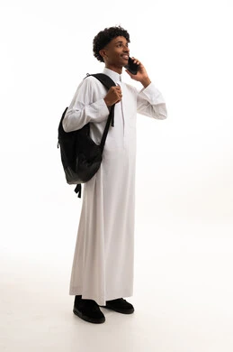 شاب سعودي بالثوب يحمل حقيبة ظهر وهاتف ذكي
