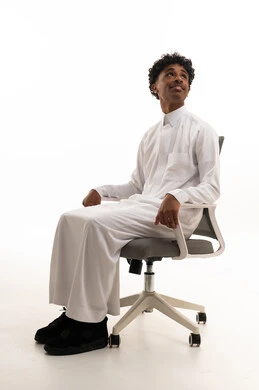 شاب سعودي بالثوب التقليدي يجلس على كرسي مكتب