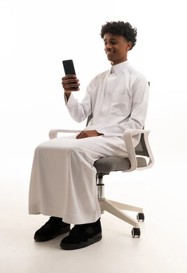 شاب سعودي يستخدم الهاتف الذكي على كرسي مكتب