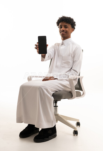 شاب سعودي بالثوب الأبيض يحمل هاتف ذكي