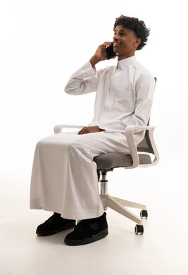 Saudi Man in Traditional Thobe Talking on Smartphone