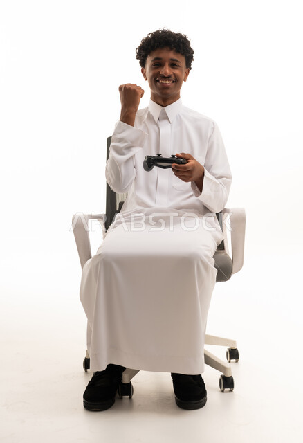 شاب سعودي بالثوب التقليدي يحتفل بالفوز في ألعاب الفيديو