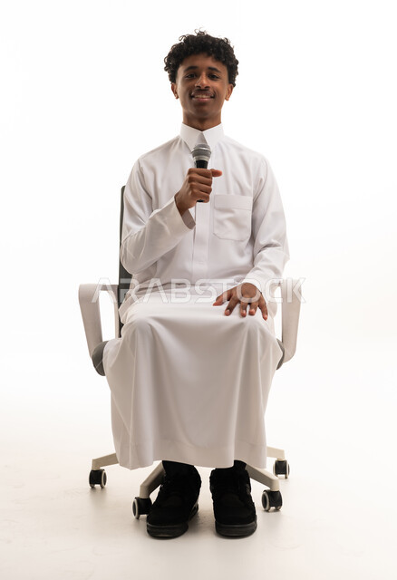 شاب سعودي بالثوب يمسك ميكروفون في استوديو
