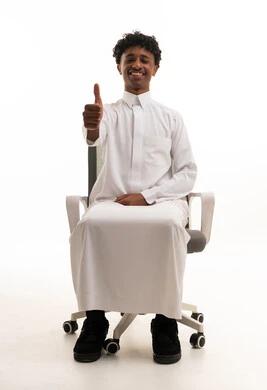 رجل سعودي بالثوب التقليدي يعطي إشارة الإبهام على كرسي مكتب