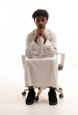 شاب سعودي بالثوب يجلس على كرسي مكتب