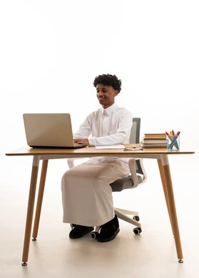 شاب سعودي بالثوب يعمل على كمبيوتر محمول