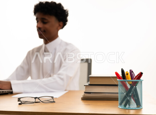 رجل سعودي بالثوب التقليدي يعمل على مكتبه