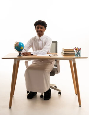 Saudi Male Student Sitting at Desk with Globe