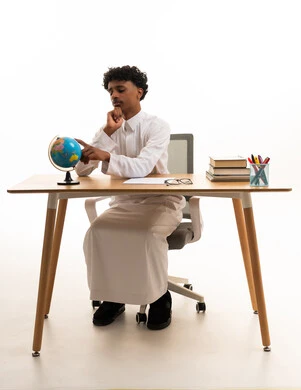 Saudi Student in Thobe Studying Globe at Office Desk