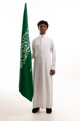 رجل سعودي يحمل علم المملكة العربية السعودية بخلفية بيضاء
