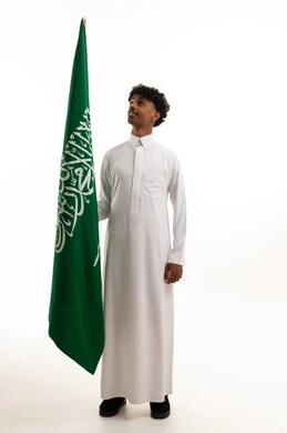 رجل سعودي بالثوب يحمل علم المملكة العربية السعودية