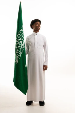 شاب سعودي يمسك بعلم السعودية بالثوب التقليدي