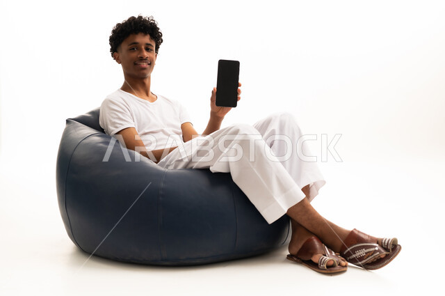 شاب سعودي يجلس على بين باج يحمل هاتف ذكي