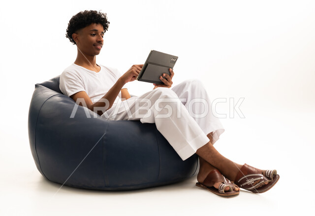 Saudi Man Using Tablet on Bean Bag Studio Shot