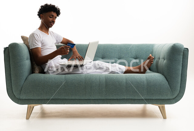 Saudi Man Using Laptop and Credit Card on Sofa