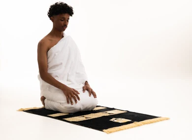 Saudi Man in Ihram Kneeling on Prayer Mat