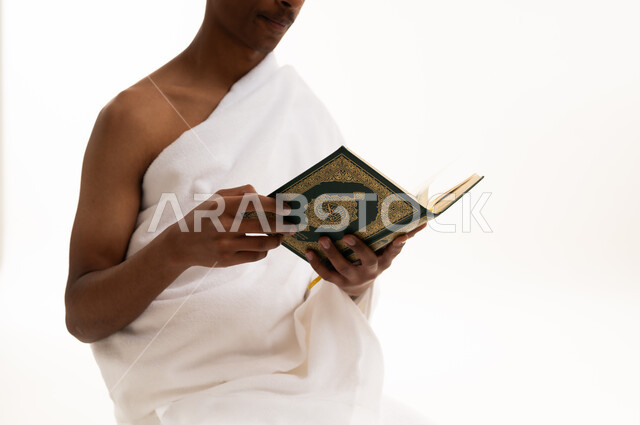 رجل سعودي بملابس الإحرام يقرأ القرآن الكريم