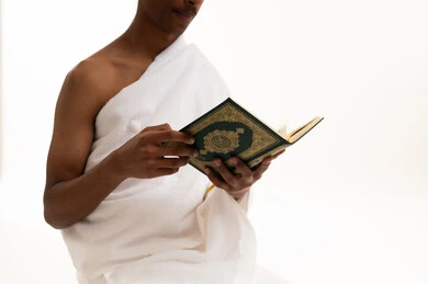 رجل سعودي بملابس الإحرام يقرأ القرآن الكريم