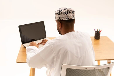 Omani Man Working on Laptop at Wooden Desk