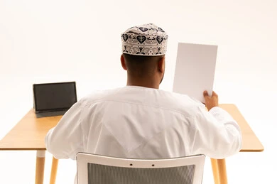 Omani Man in Traditional Dress at Office Desk
