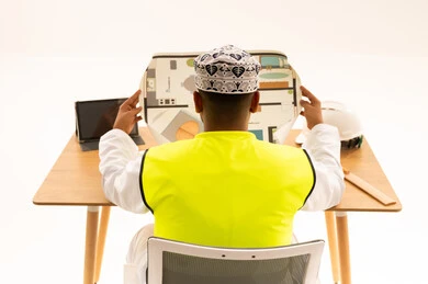 Omani Architect Reviewing Floor Plan with Safety Gear