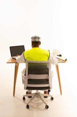 Omani Engineer at Desk with Safety Vest and Laptop