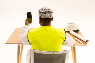 Omani Engineer Holding Green Screen Smartphone at Desk