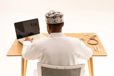 Omani Doctor Working on Laptop with Medical Tools