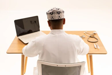 Omani Male Doctor Working on Laptop in Clinical Office