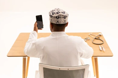 طبيب عماني بالكمة التقليدية يستخدم الهاتف الذكي