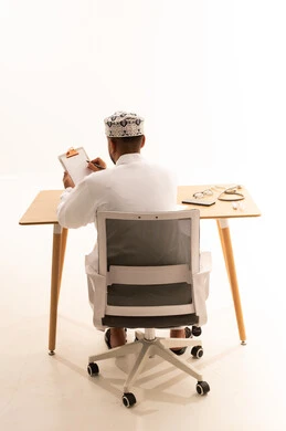 Omani Doctor Writing at Desk in Traditional Dress