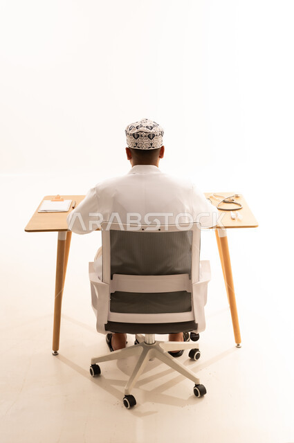 طبيب عُماني بالزي التقليدي يجلس خلف مكتبه