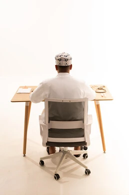 Omani Doctor in Traditional Dress at Desk Back View