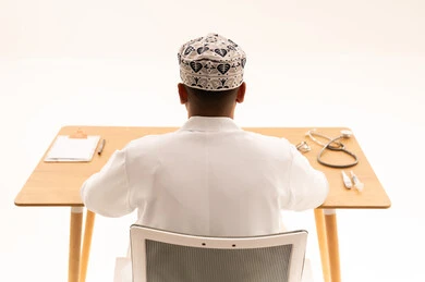 Omani Doctor in Traditional Kumma at Medical Desk