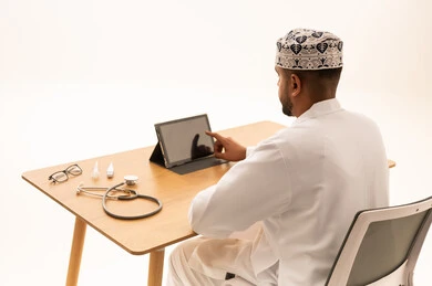 طبيب عُماني يستخدم جهازاً لوحياً في مكتب طبي