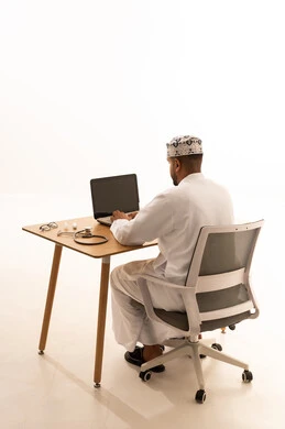 Omani Doctor Working on Laptop in White Studio