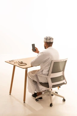 Omani Professional at Desk with Smartphone and Stethoscope