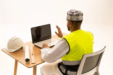 مهندس عماني يستخدم الحاسوب مع معدات السلامة