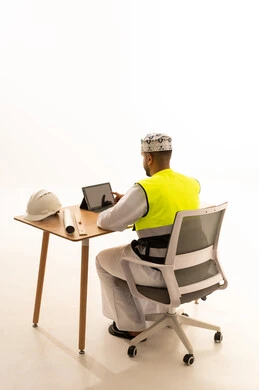 Omani Engineer in Safety Vest Using Tablet at Desk