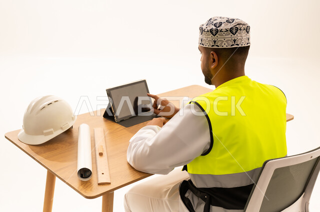 مهندس عماني يرتدي سترة السلامة ويستخدم جهاز لوحي