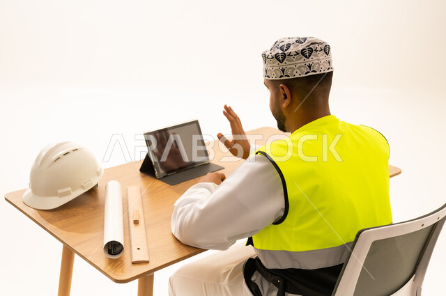 مهندس عماني يرتدي سترة السلامة ويستخدم جهاز لوحي