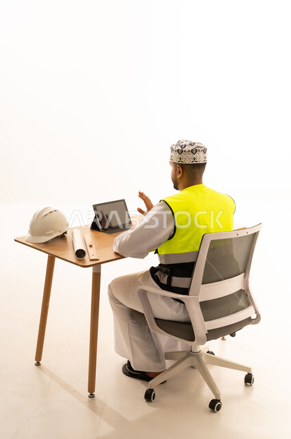 Omani Engineer with Tablet and Safety Gear at Desk