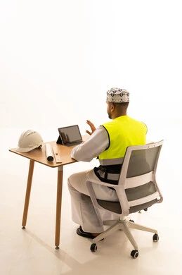 Omani Engineer with Tablet and Safety Gear at Desk