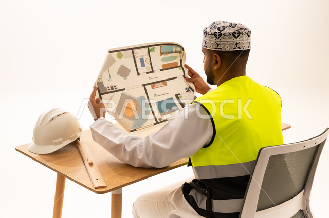 مهندس عماني بالزي التقليدي يراجع مخطط بناء