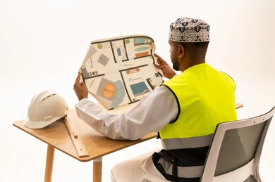 Omani Engineer in Traditional Dress Reviewing Floor Plan