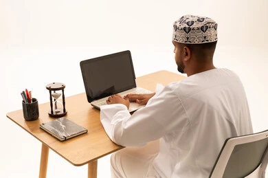 Omani Man Working on Laptop at Office Desk